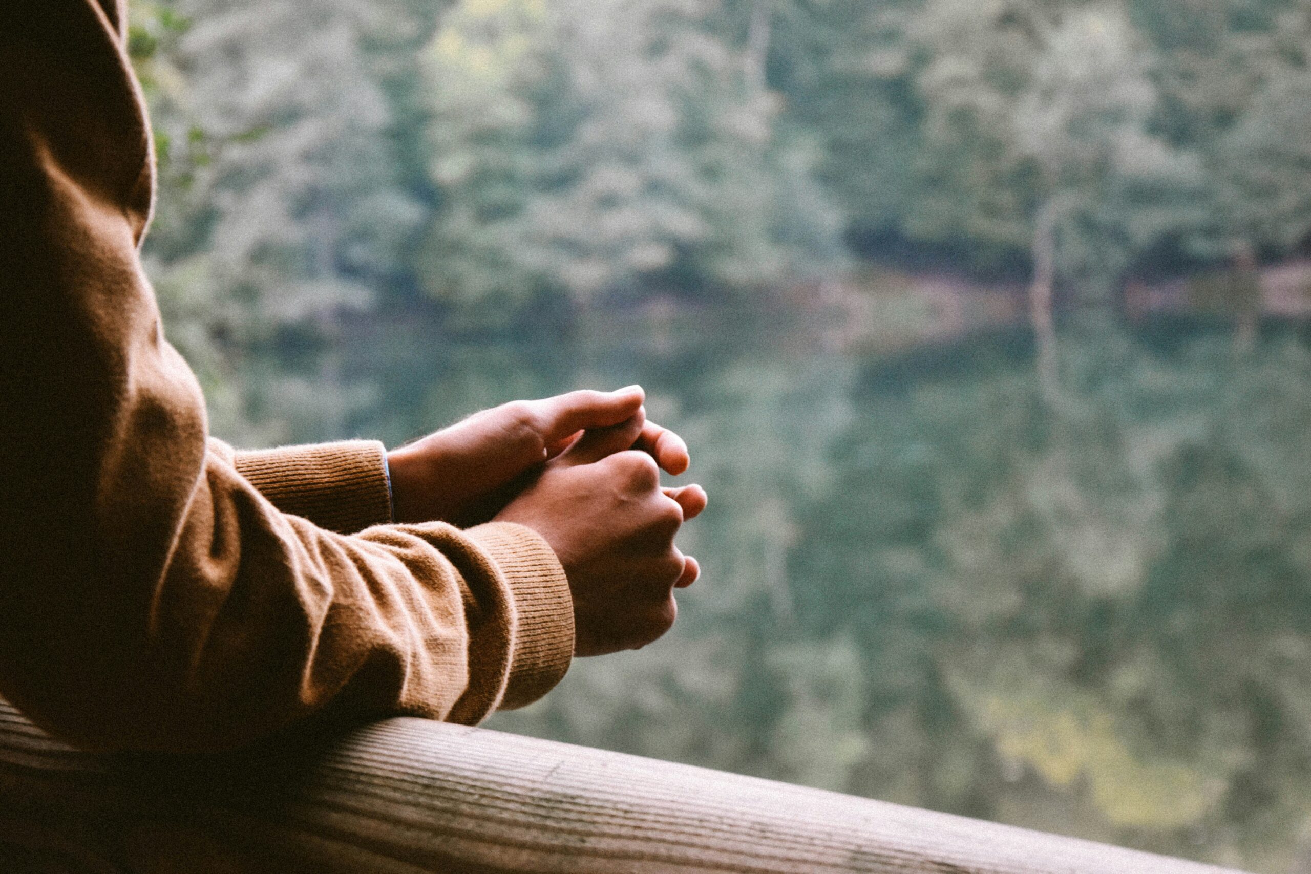 Woman, cropped, staring at a lake surrounded by trees